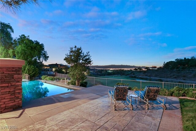 pool at dusk featuring a patio