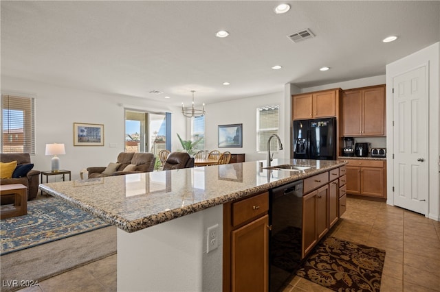 kitchen featuring black appliances, a kitchen island with sink, tile patterned floors, a wealth of natural light, and light stone counters