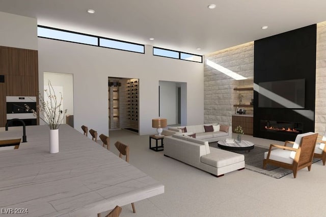 living room featuring a high ceiling, carpet, a glass covered fireplace, and recessed lighting