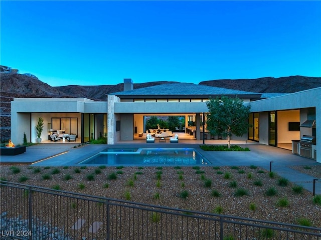 view of pool featuring an outdoor living space, a patio area, a mountain view, grilling area, and an outdoor kitchen