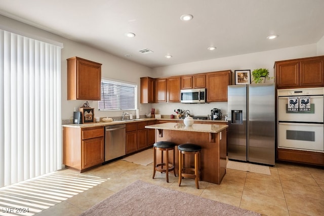 kitchen featuring a breakfast bar area, sink, a center island, light tile patterned floors, and appliances with stainless steel finishes