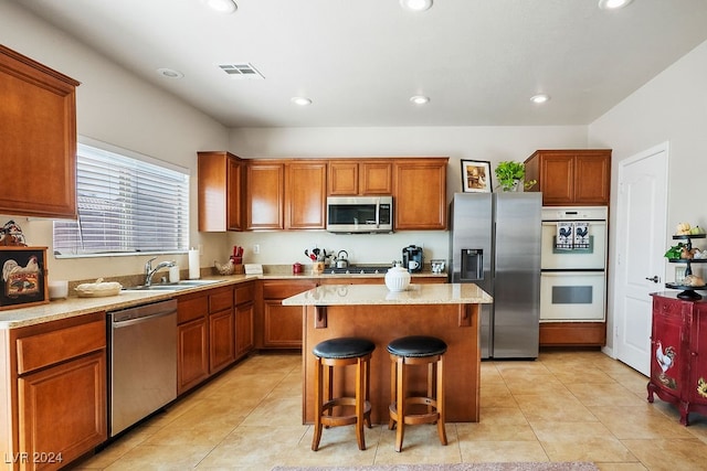 kitchen featuring appliances with stainless steel finishes, sink, a kitchen island, a kitchen breakfast bar, and light tile patterned floors