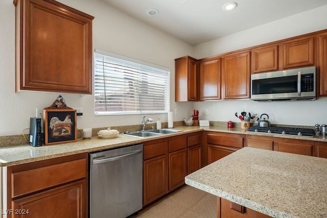 kitchen featuring appliances with stainless steel finishes, sink, and light stone counters