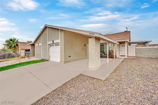 view of front of home with driveway, an attached garage, fence, and stucco siding