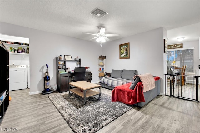 living area featuring light wood finished floors, visible vents, a ceiling fan, washing machine and clothes dryer, and a textured ceiling