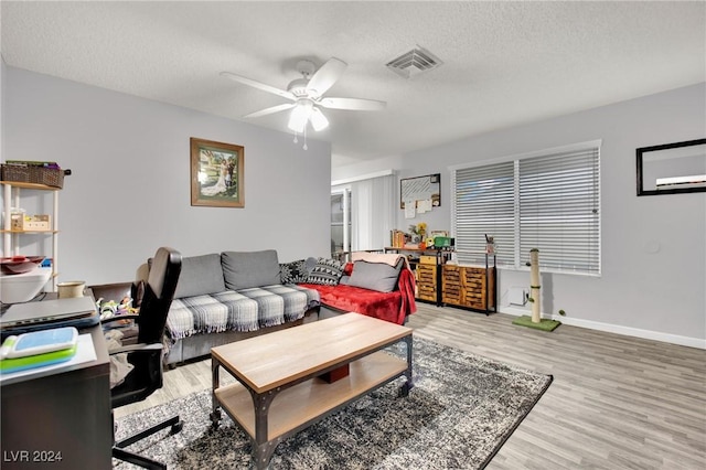 living area with visible vents, a textured ceiling, baseboards, and wood finished floors