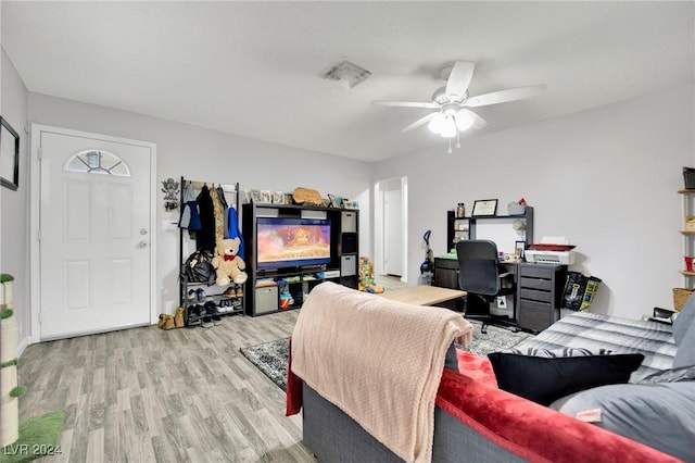 living room with visible vents, light wood-type flooring, and a ceiling fan