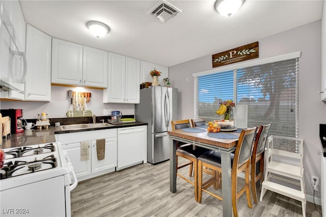 kitchen featuring white appliances, a sink, visible vents, white cabinetry, and dark countertops