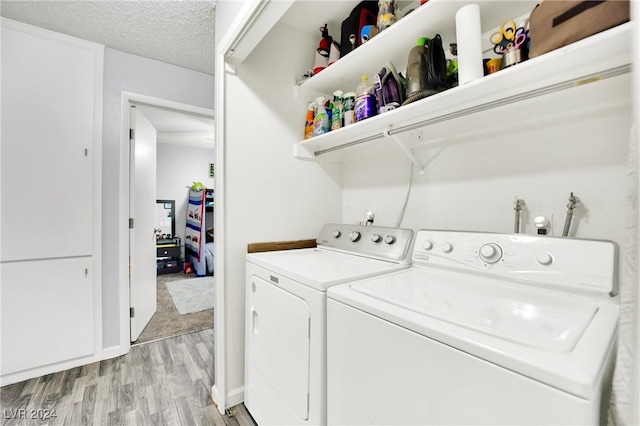 laundry room featuring a textured ceiling, light wood-type flooring, independent washer and dryer, and laundry area