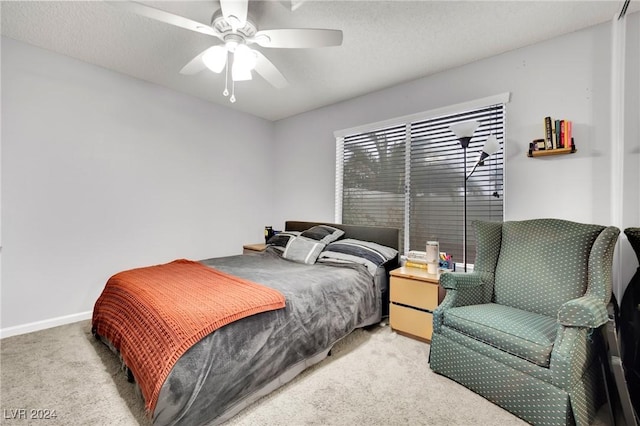 bedroom featuring a textured ceiling, baseboards, a ceiling fan, and light colored carpet