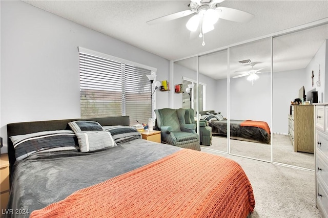 bedroom with a ceiling fan, a closet, light carpet, and a textured ceiling