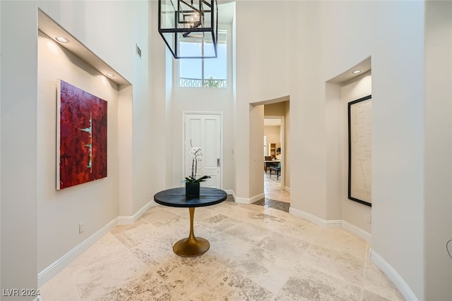 interior space with light tile patterned floors, a high ceiling, and a notable chandelier