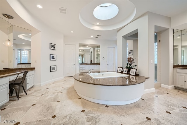 bathroom with a bathing tub, a raised ceiling, vanity, and tile patterned floors