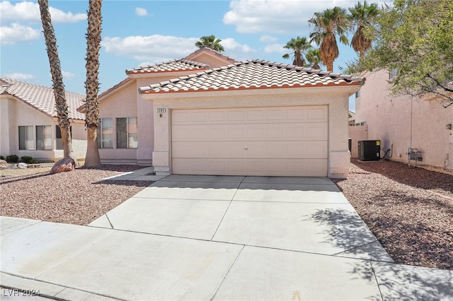 mediterranean / spanish-style house with a garage and central AC unit