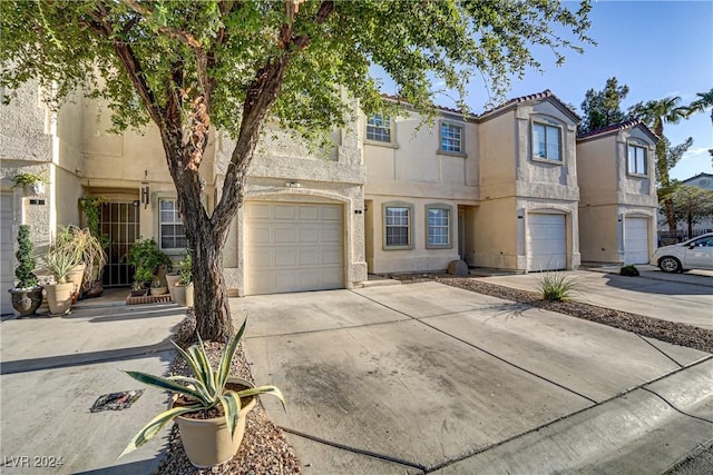 view of property featuring a garage, concrete driveway, and stucco siding