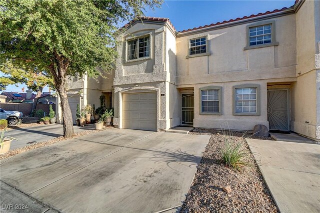 view of front of home with a garage, concrete driveway, a tiled roof, and stucco siding