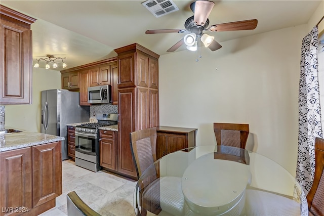 kitchen with light tile patterned floors, appliances with stainless steel finishes, ceiling fan, and light stone counters