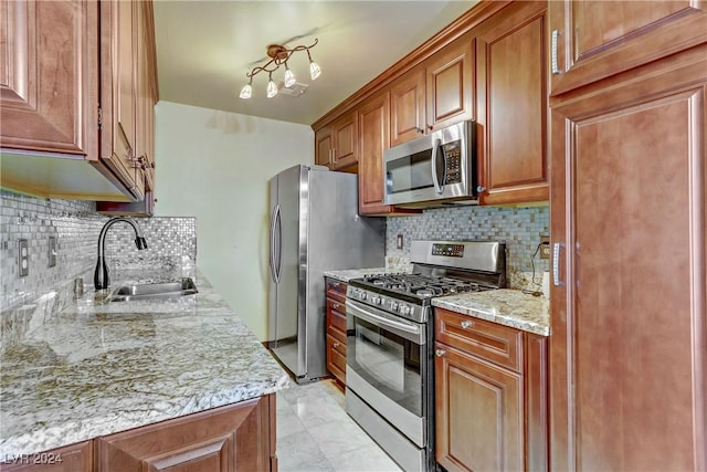 kitchen with stainless steel appliances, tasteful backsplash, brown cabinetry, a sink, and light stone countertops