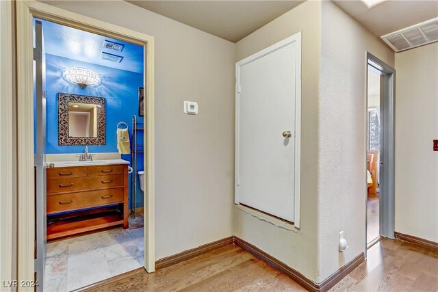 corridor featuring a sink, baseboards, visible vents, and wood finished floors