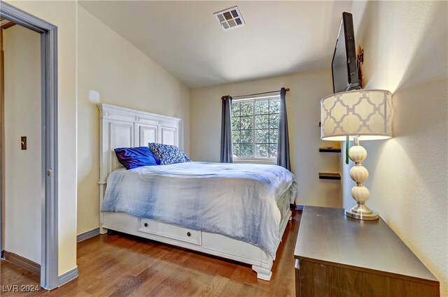 bedroom featuring lofted ceiling, dark wood-style flooring, visible vents, and baseboards