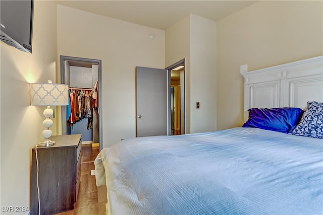 bedroom featuring a spacious closet, a closet, hardwood / wood-style floors, and a high ceiling