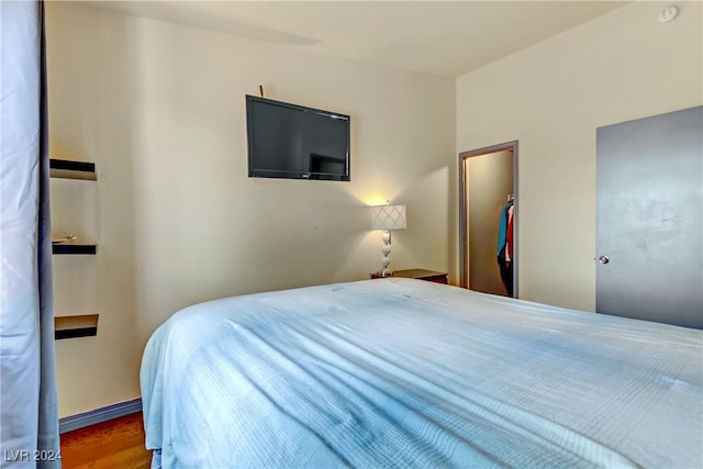 bedroom featuring a closet, a spacious closet, baseboards, and wood finished floors