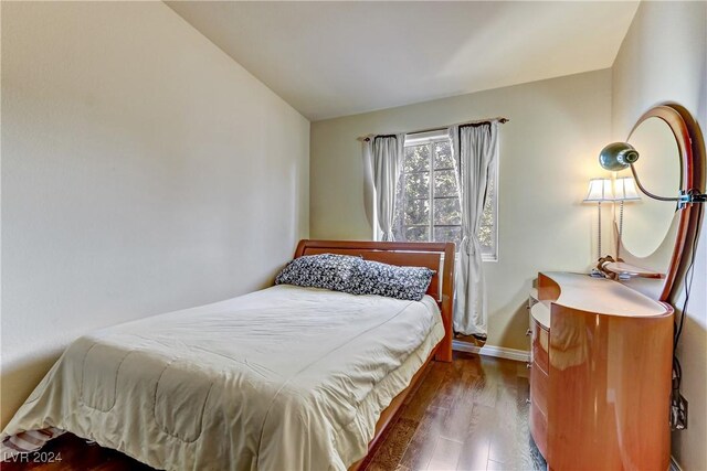 bedroom with vaulted ceiling and dark hardwood / wood-style flooring