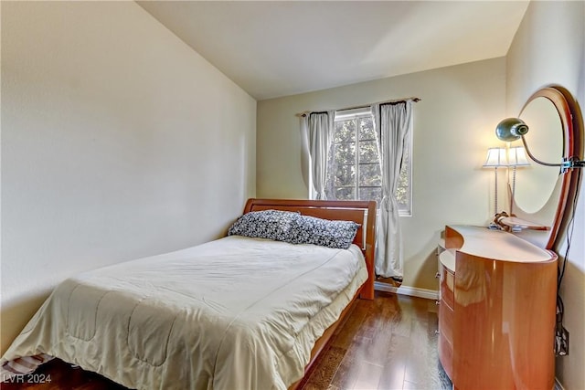 bedroom featuring dark wood-style flooring, vaulted ceiling, and baseboards