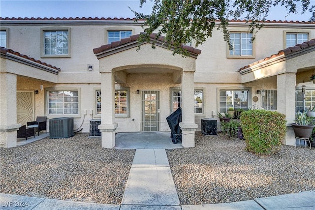 entrance to property with cooling unit, a patio area, and stucco siding