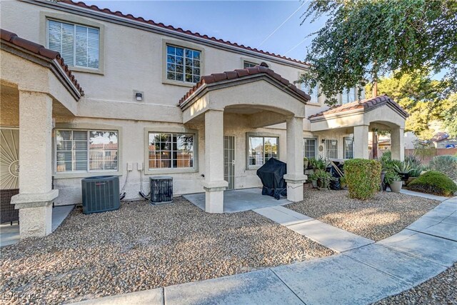 view of front of house with a tile roof, fence, central AC, and stucco siding