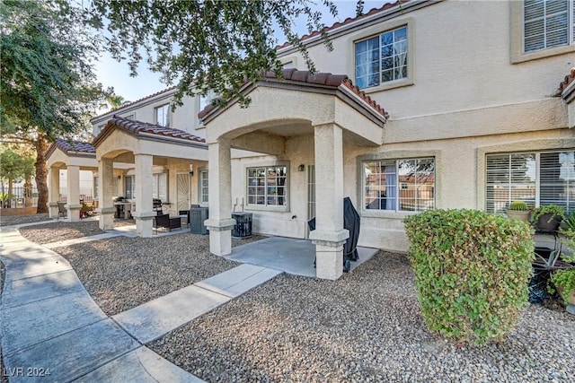 view of exterior entry featuring a patio, a tiled roof, and stucco siding