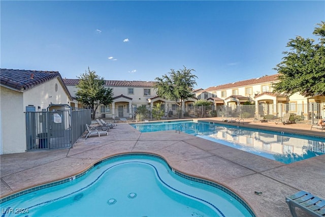 community pool featuring a patio, fence, and a residential view