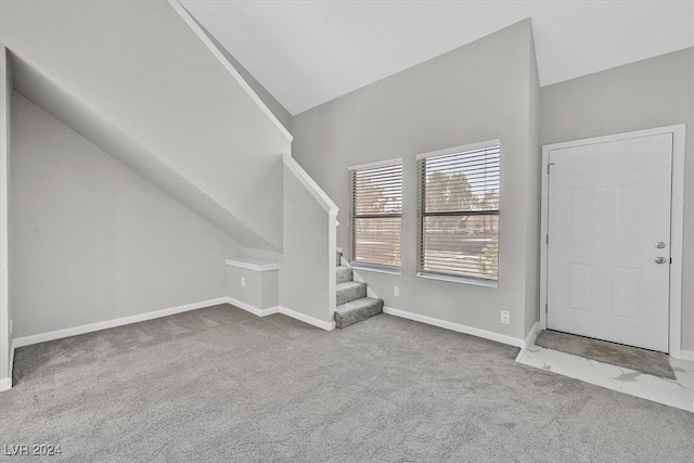 entrance foyer featuring carpet floors and high vaulted ceiling