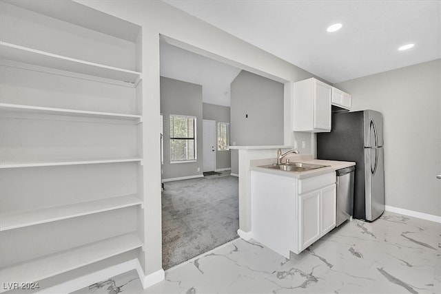 kitchen with sink, appliances with stainless steel finishes, white cabinetry, and light carpet