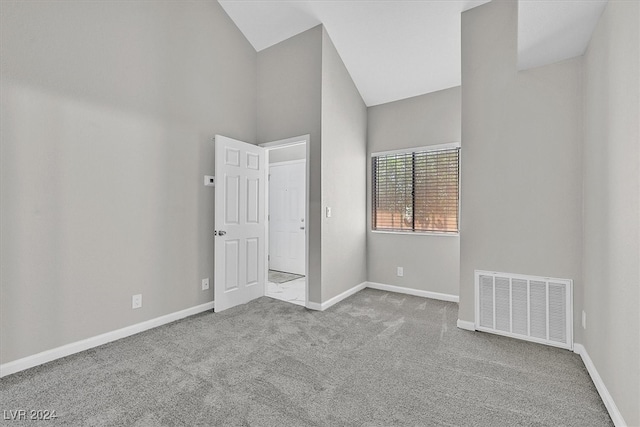 unfurnished bedroom featuring carpet and high vaulted ceiling