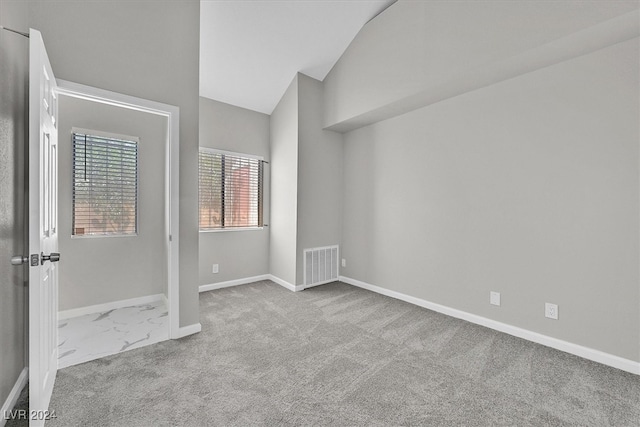 empty room featuring lofted ceiling and light carpet