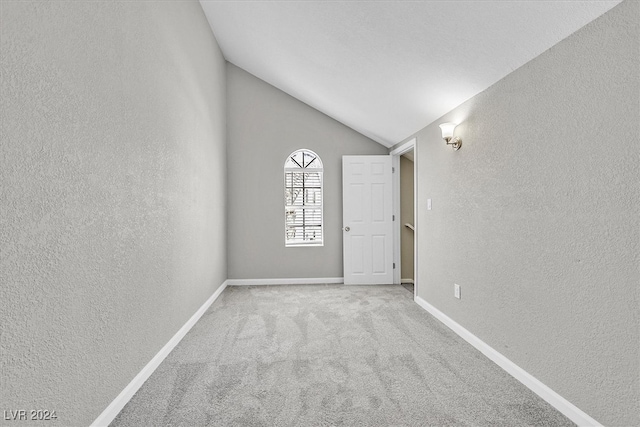 carpeted spare room featuring lofted ceiling