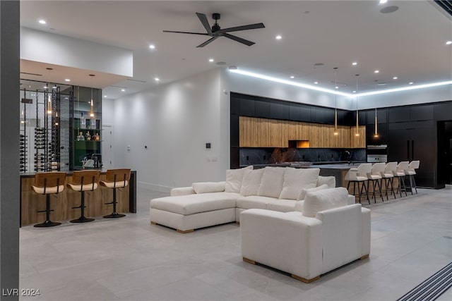 living room featuring ceiling fan, sink, a high ceiling, and light tile patterned floors