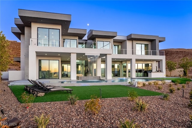 back of house featuring a balcony, a patio area, and a yard