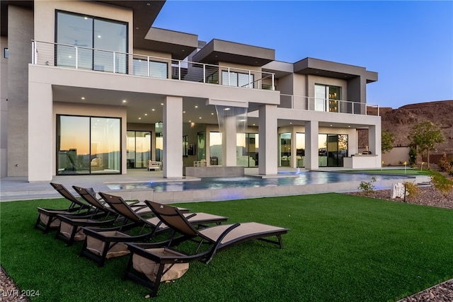 rear view of property with a patio, a yard, and a balcony