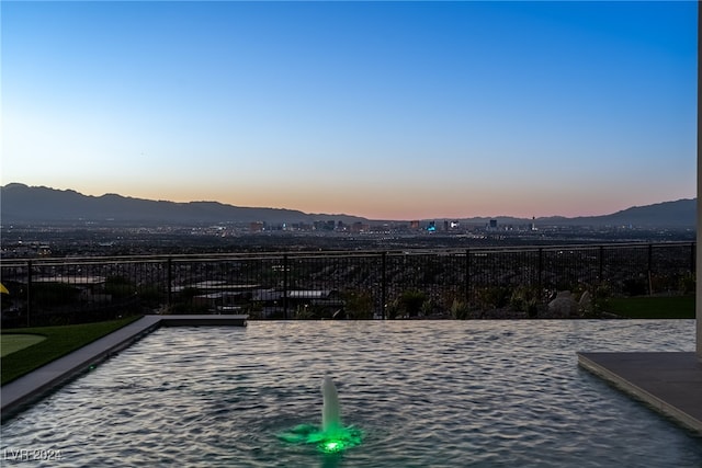 pool at dusk featuring a mountain view