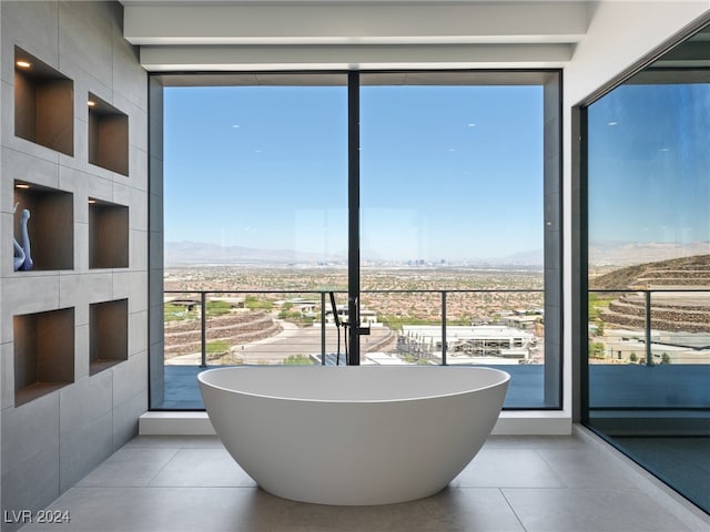 bathroom with tile walls, a tub, and tile patterned floors