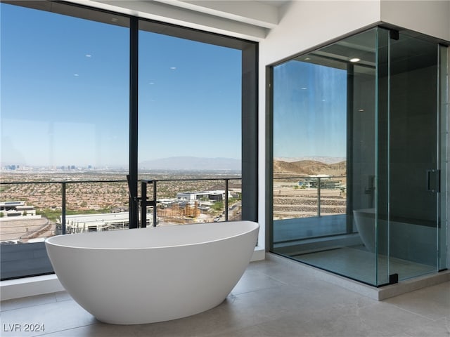 bathroom with a mountain view, shower with separate bathtub, plenty of natural light, and tile patterned floors