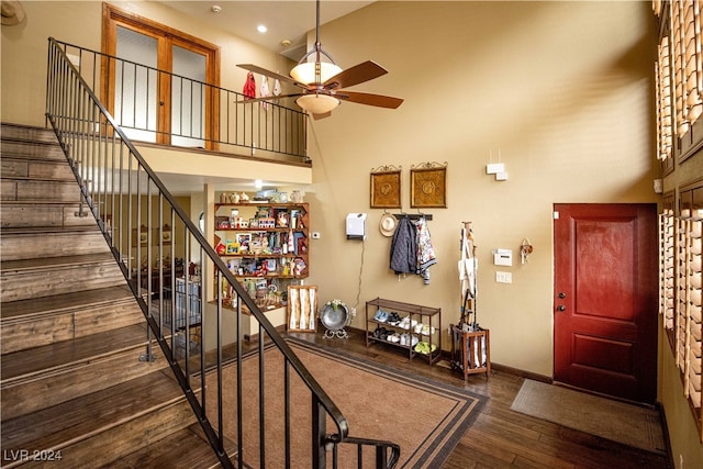 entryway featuring ceiling fan, dark wood-type flooring, and a high ceiling