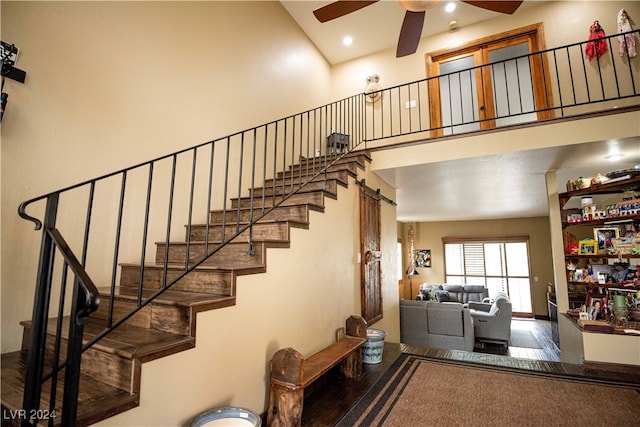 stairway with ceiling fan, hardwood / wood-style flooring, and a high ceiling