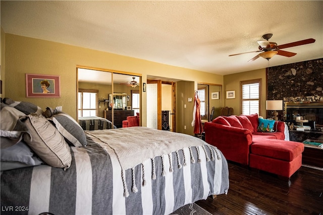 bedroom featuring ceiling fan, multiple closets, hardwood / wood-style flooring, and a textured ceiling