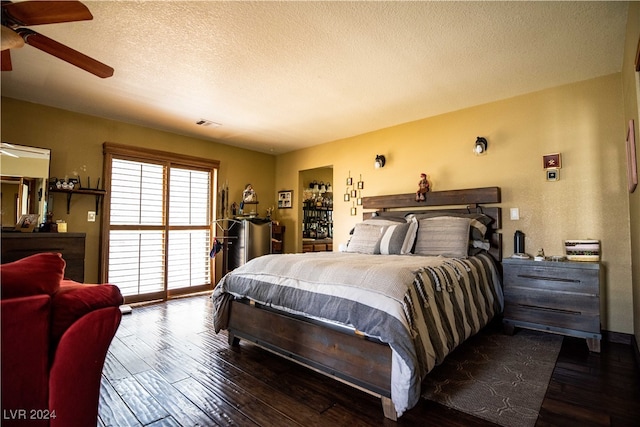 bedroom featuring ceiling fan, dark hardwood / wood-style floors, and a textured ceiling