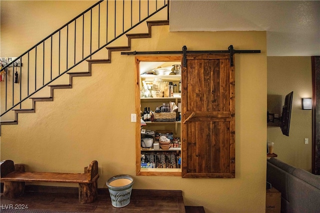 stairs with a barn door and wood-type flooring