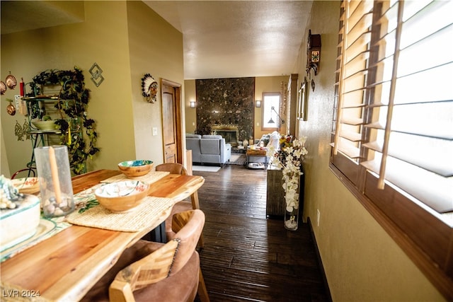 dining space with a fireplace, dark wood-type flooring, and a textured ceiling