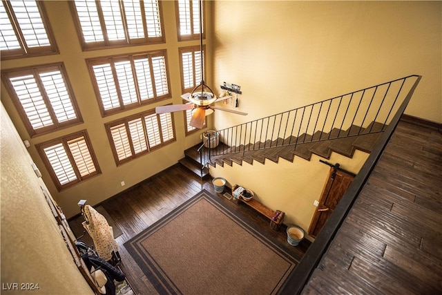 stairs featuring a high ceiling, ceiling fan, and wood-type flooring